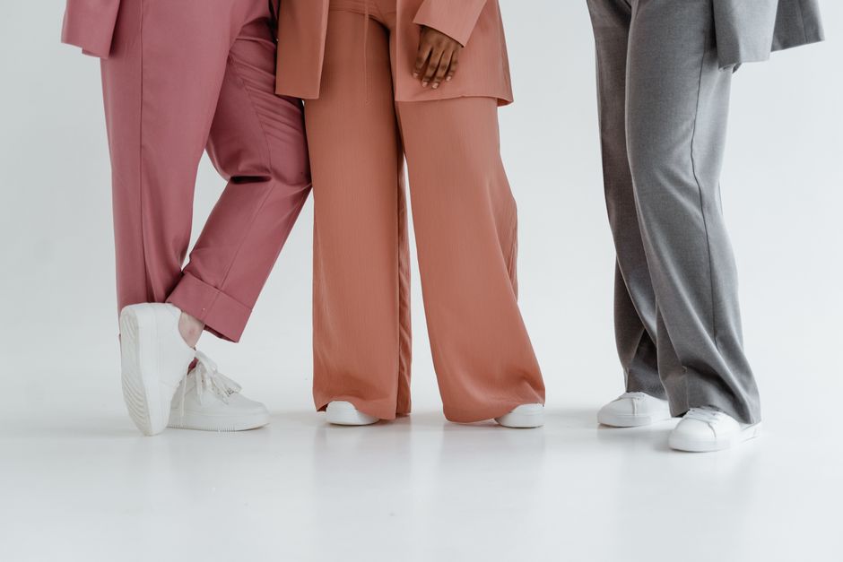 A professional woman in a bright office environment, wearing tailored wide-leg trousers, a tucked-in blouse, and sophisticated flats, showcasing a polished work outfit.