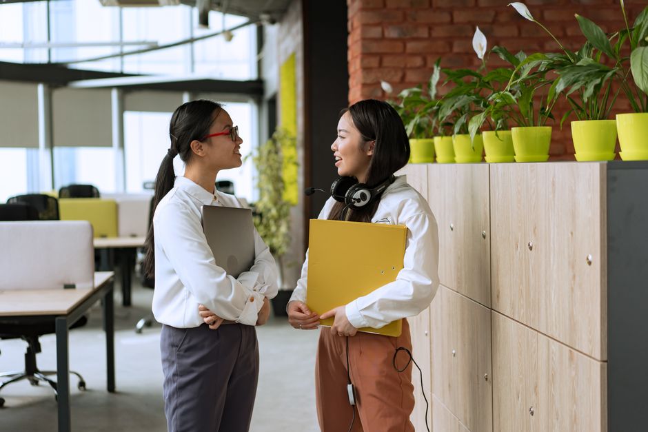 Three office workers, two men and one woman, engaged in a discussion while looking at a whiteboard with diagrams, suggesting strategic planning around AI integration.