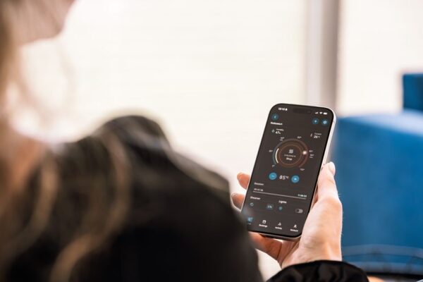 An old smartphone mounted on a wall displaying smart home controls like lights and thermostat settings.
