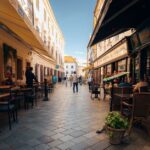 A charming, narrow European street scene with outdoor cafes, local residents enjoying coffee, and a tram passing by, emphasizing local life and transit.