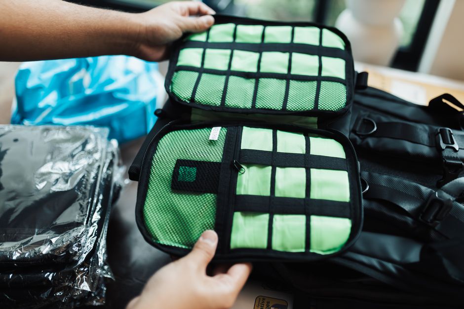 An open travel backpack, organized with colorful packing cubes for clothes, a laptop in its dedicated sleeve, and other essentials, showcasing efficient packing.