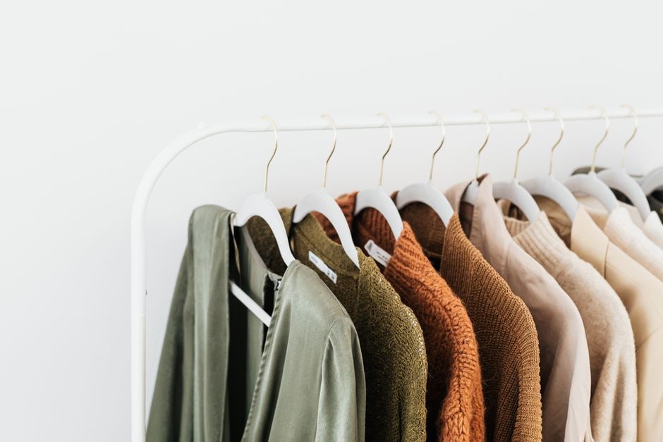 A neatly organized capsule wardrobe featuring timeless, high-quality garments in neutral colors, arranged in a closet.