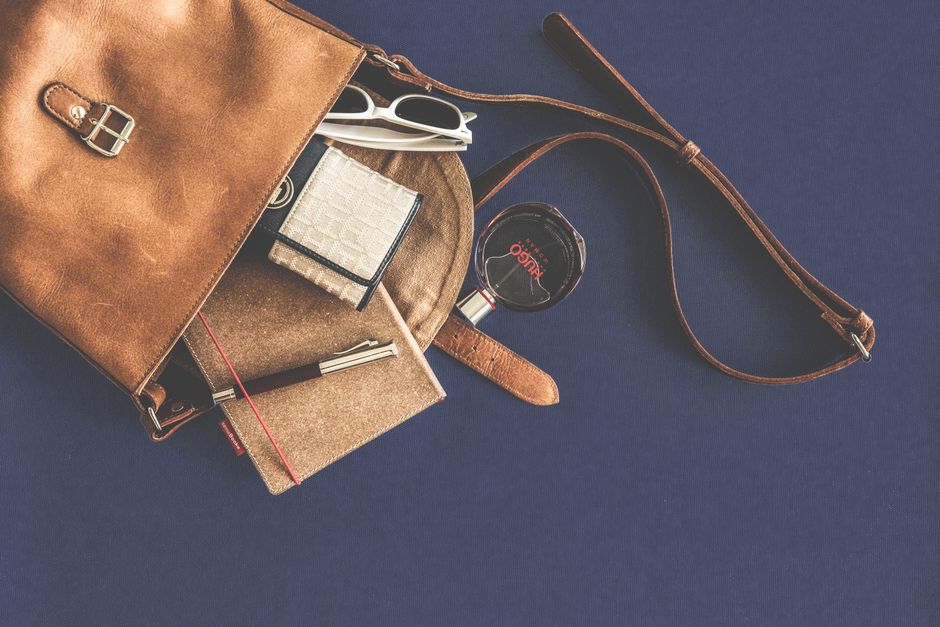 A neatly organized bag displaying essential commute items: headphones, e-reader, water bottle, and portable charger.