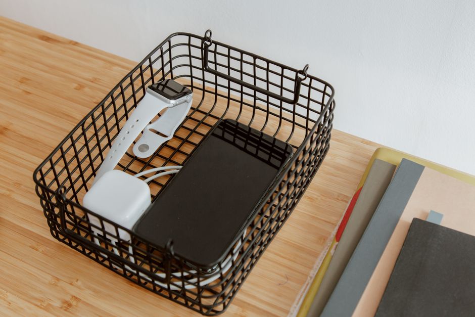 A neatly organized desk with a multi-device charging station, showing a tablet, smartphone, and headphones charging in designated spots.