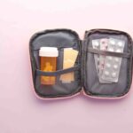 A neatly organized travel first aid kit with various medical supplies laid out on a table, including bandages, antiseptic wipes, and small bottles of medication.