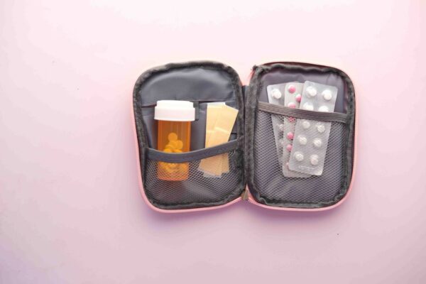 A neatly organized travel first aid kit with various medical supplies laid out on a table, including bandages, antiseptic wipes, and small bottles of medication.