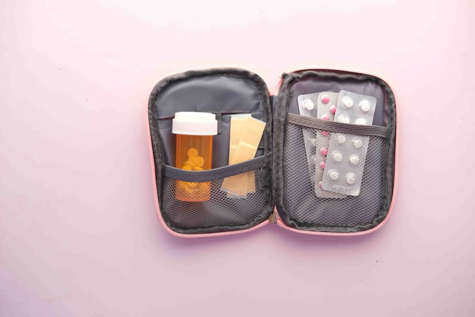 A neatly organized travel first aid kit with various medical supplies laid out on a table, including bandages, antiseptic wipes, and small bottles of medication.
