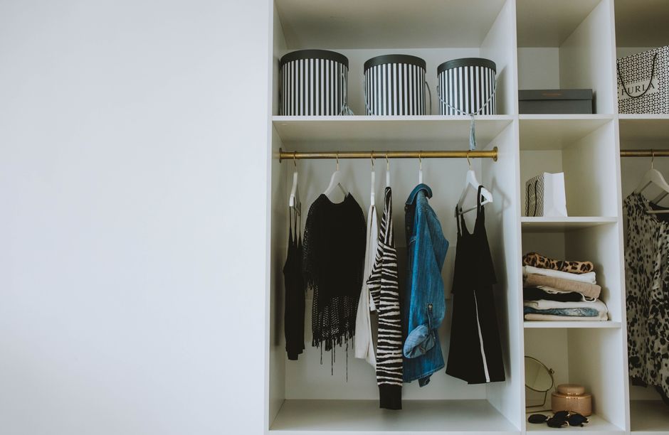 An organized closet with a capsule wardrobe featuring neutral-colored clothes neatly hung, showing easy outfit combinations.