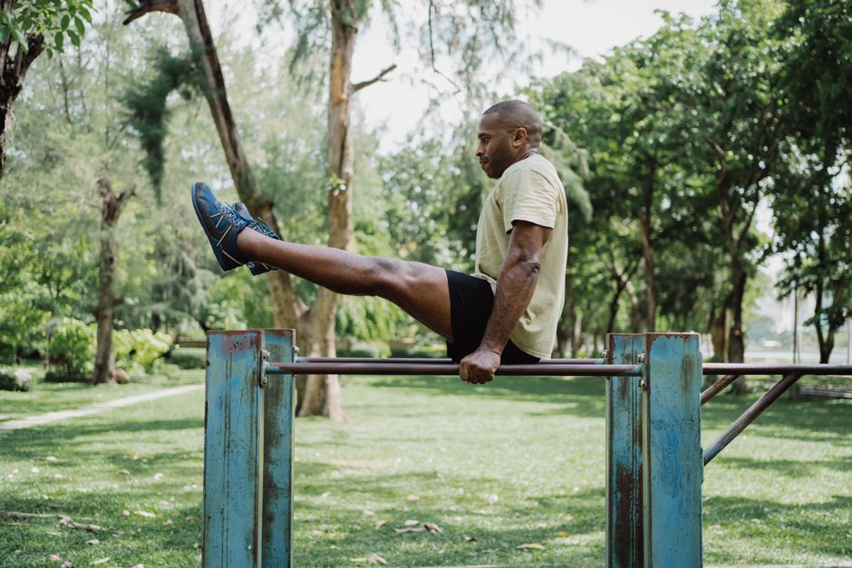 A person doing squats in a public park with trees in the background, demonstrating outdoor bodyweight training.