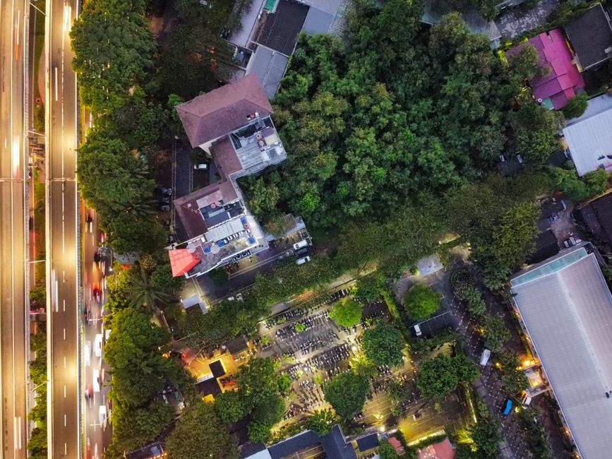 Aerial view of a large, lush green park, like Chapultepec, surrounded by the high-rises and dense infrastructure of a major city.
