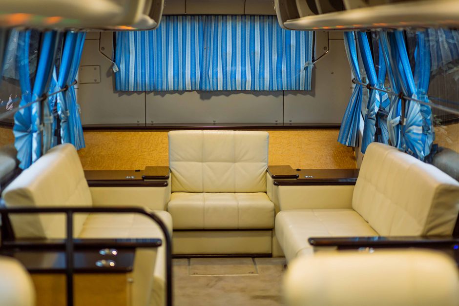 The interior of a comfortable, modern long-distance bus in South America, showing reclining 'cama' seats with pillows and blankets, suggesting a restful journey.