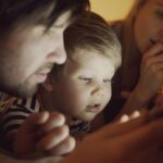 A parent and child looking at a tablet screen together, possibly reviewing settings or a game.
