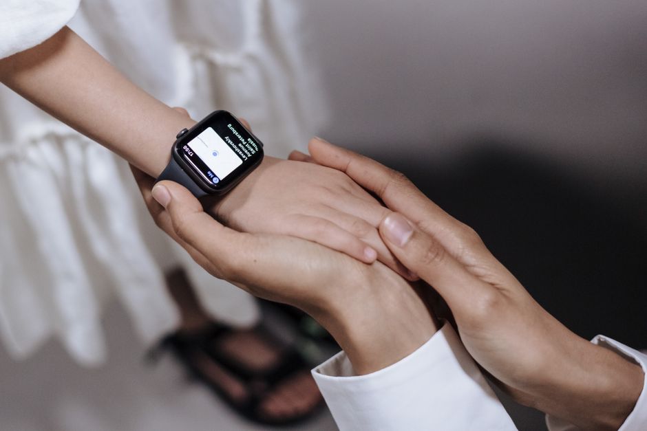 A parent gently rocking a baby in a softly lit nursery, while subtly glancing at their smartwatch, depicting the real-world challenges and opportunities for sleep tracking among caregivers.