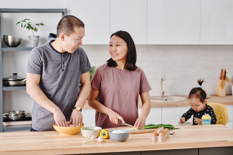 Overhead shot of a parent actively chopping vegetables and preparing multiple healthy meals in a clean kitchen, with containers ready for storage.