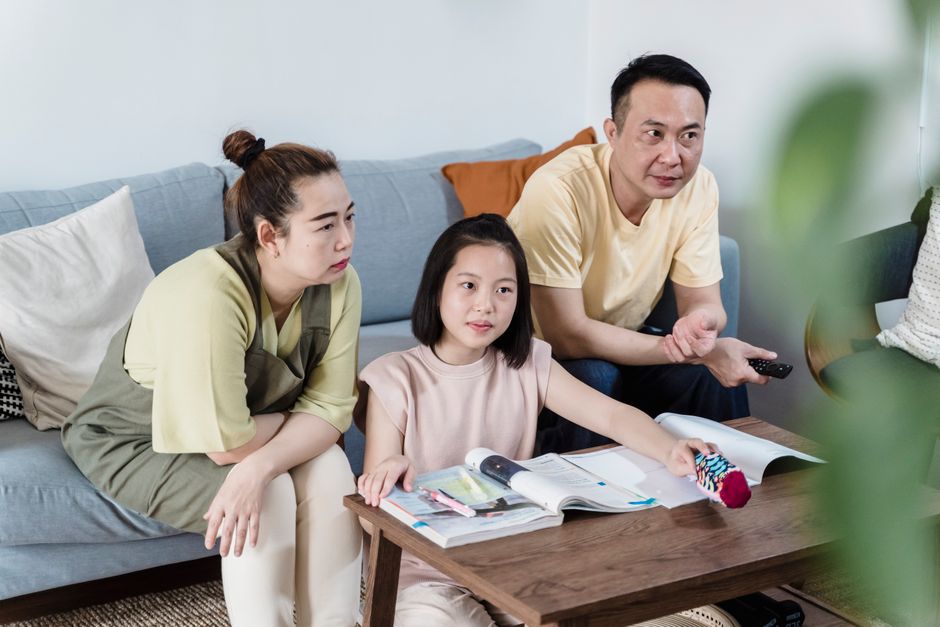 A parent demonstrating how to set up parental controls on a laptop to a child, with a clear interface showing settings for content restrictions.