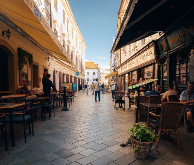 People enjoying a leisurely walk past outdoor cafes on a charming European pedestrian street, highlighting the ease of daily walking.