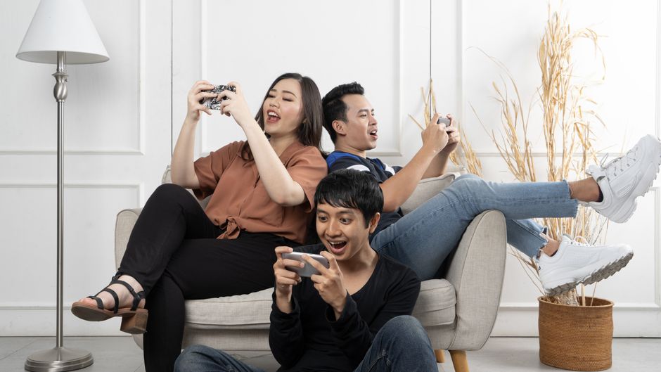 Diverse group of people of various ages playing mobile games on their smartphones in a public park, illustrating global mobile gaming trends.