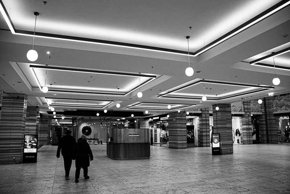 Several individuals walking and chatting inside a spacious, well-lit shopping mall during winter.