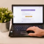 A person's hand hovering a mouse cursor over a suspicious link in an email, with red flags like a mismatched URL visible on the screen, illustrating how to spot phishing emails.