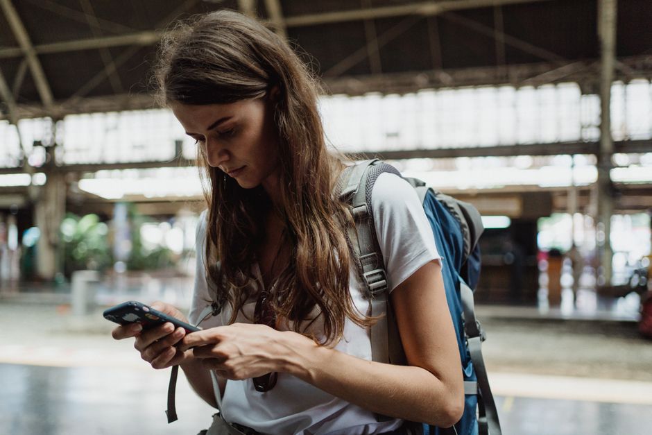 A traveler in a bustling European street, possibly in Rome, using a smartphone to navigate, showcasing its utility for travel.