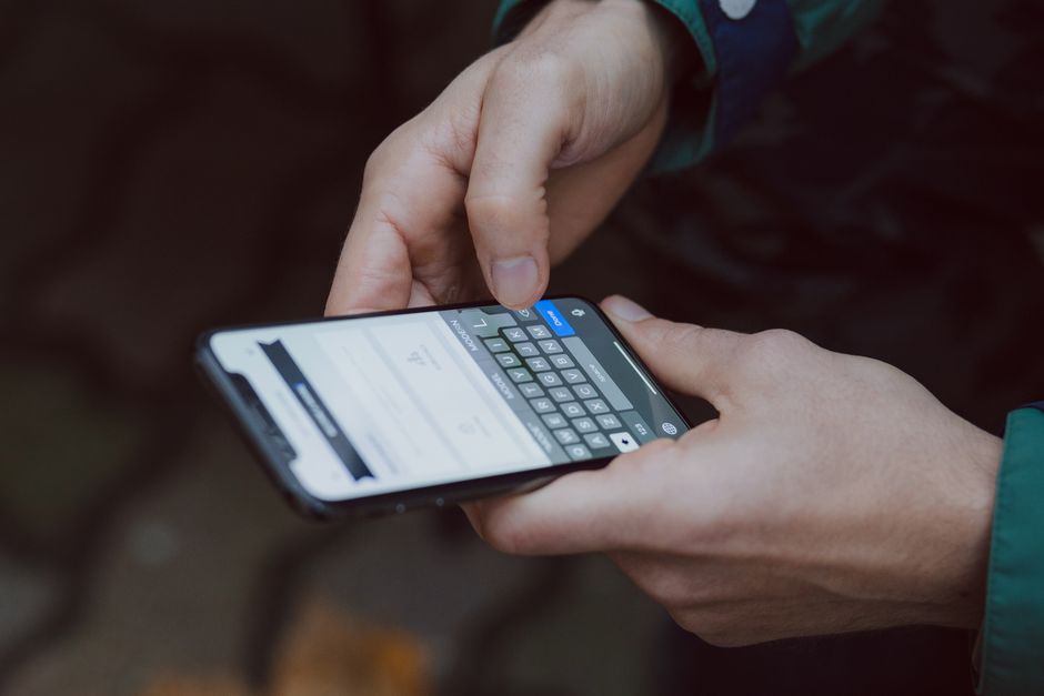 A person's hand holding a smartphone, actively navigating through Wi-Fi settings to adjust security preferences.