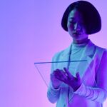 A person interacting with an AI interface projected as a hologram, symbolizing collaboration between humans and AI in a modern workplace.