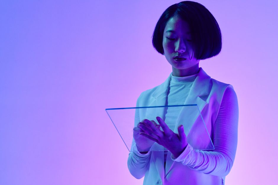 A person interacting with an AI interface projected as a hologram, symbolizing collaboration between humans and AI in a modern workplace.