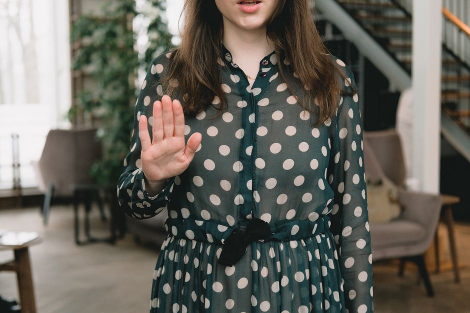 A person at a coffee shop politely but firmly declines an offer, gesturing 'no' with a clear and confident expression, representing setting boundaries.