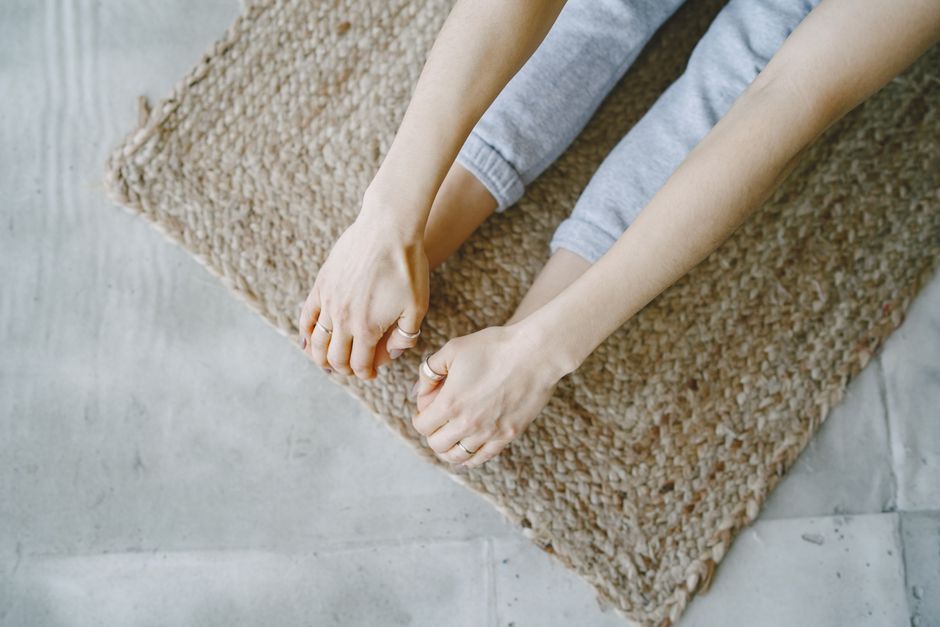 A person in comfortable clothes performing a gentle yoga stretch on a mat in a bright living room. Focuses on easy, accessible movement.