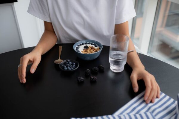 A person enjoying a bowl of Greek yogurt topped with fresh berries, representing an easy, high-protein breakfast.