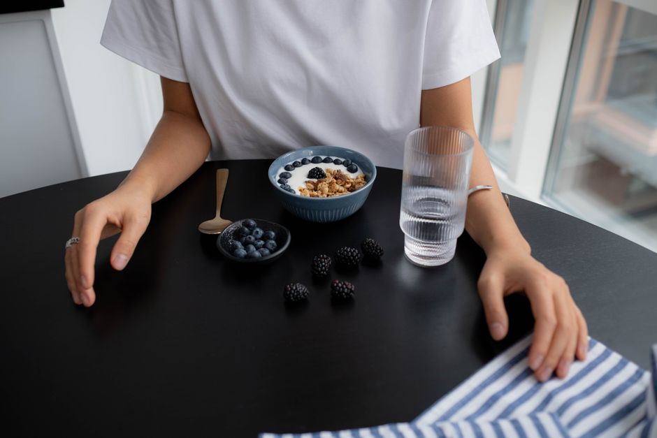 A person enjoying a bowl of Greek yogurt topped with fresh berries, representing an easy, high-protein breakfast.