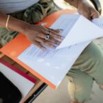 A person with glasses meticulously reviewing printed documents and digital text, symbolizing human editorial oversight.