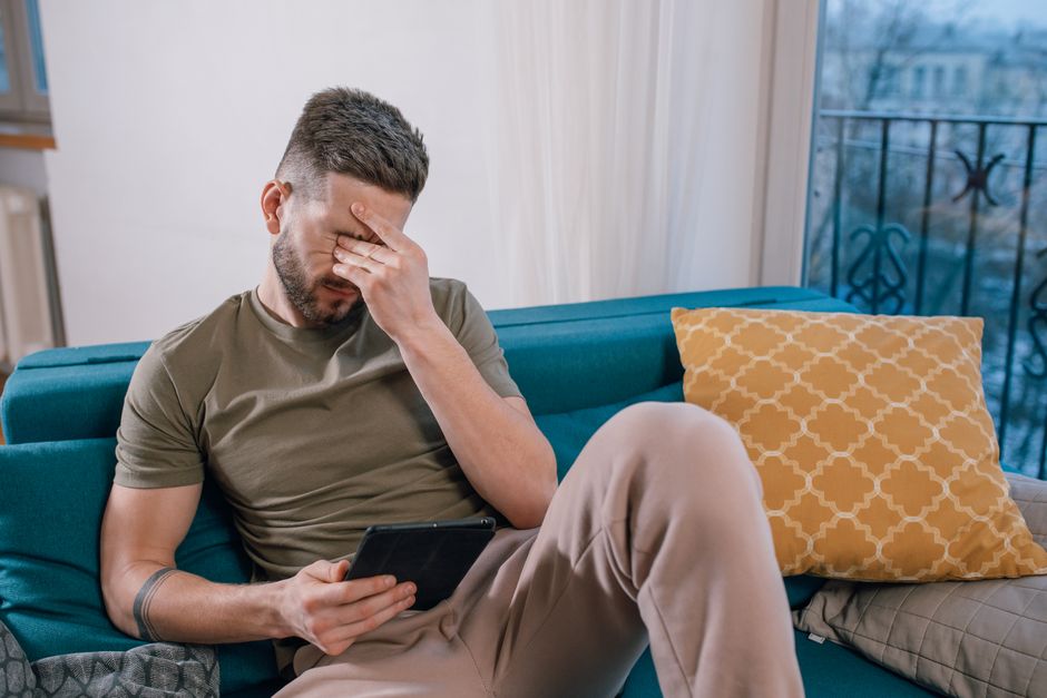 A person with a worried expression, sitting at a desk and overwhelmed by too much data from various health apps open on a laptop and phone.