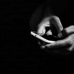A person's hand holding a modern smartphone, scrolling through content, showing the user experience.