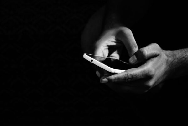 A person's hand holding a modern smartphone, scrolling through content, showing the user experience.