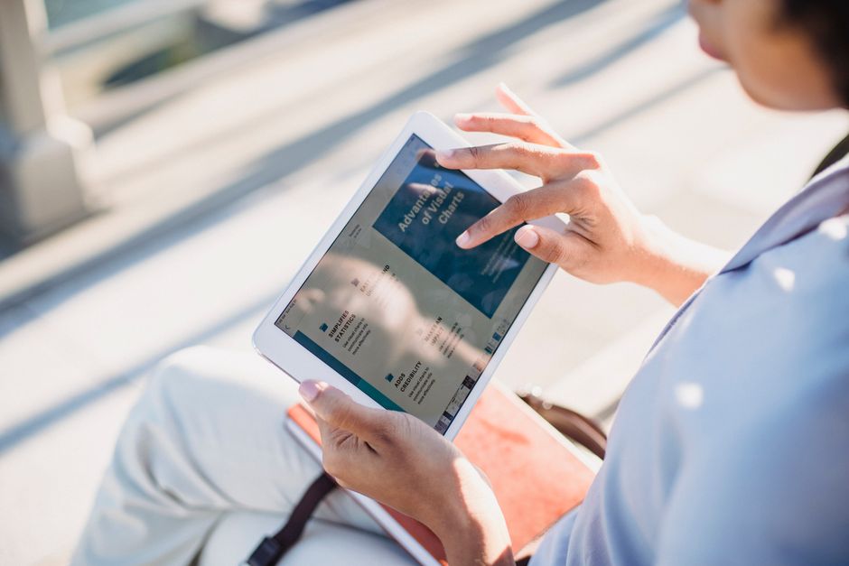 Person comfortably holding a tablet, reading an e-book with a cup of coffee nearby, illustrating the reading experience.