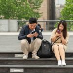 A person reading a physical book, with a smartphone placed face down next to them, symbolizing a choice to disconnect and create boundaries.