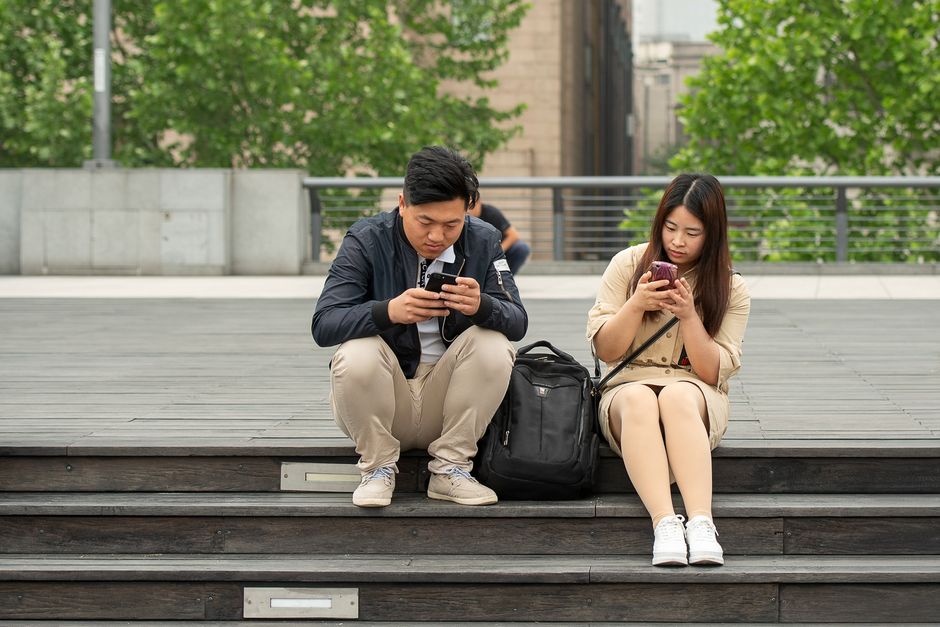 A person reading a physical book, with a smartphone placed face down next to them, symbolizing a choice to disconnect and create boundaries.