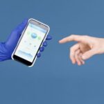 A person holding a smartphone, looking at a healthcare application interface displaying graphs and health metrics.