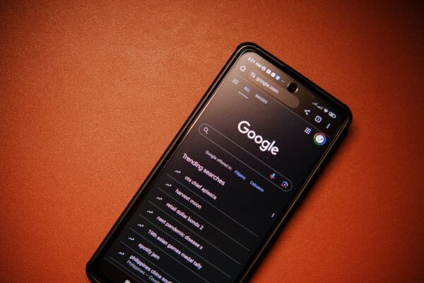 A person holding a smartphone showing an AI Overview result on a search page, with traditional blue links visible below it, against a blurred background.