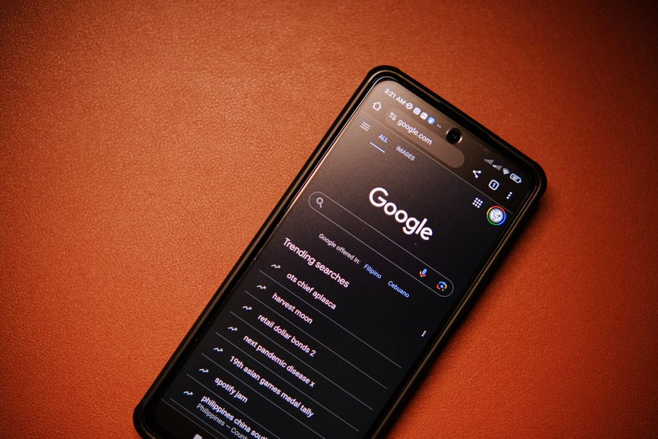 A person holding a smartphone showing an AI Overview result on a search page, with traditional blue links visible below it, against a blurred background.