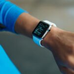 A busy professional examining a digital health app on a smartwatch, showing various health metrics like steps, heart rate, and sleep score.