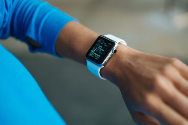 A busy professional examining a digital health app on a smartwatch, showing various health metrics like steps, heart rate, and sleep score.