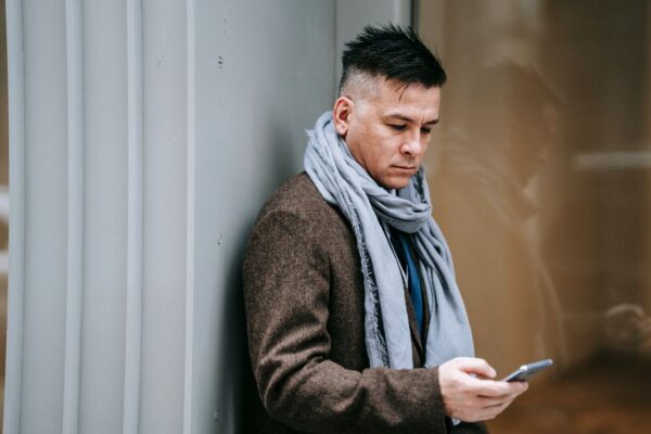 A person with a confused expression holding a smartphone, with a blurred background showing various digital icons, representing online confusion.