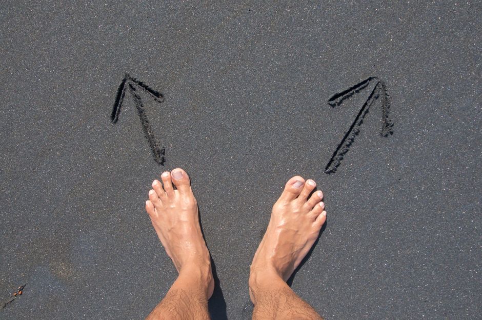 A person standing at a crossroads with multiple signs, looking overwhelmed by the choices ahead, symbolizing decision fatigue.