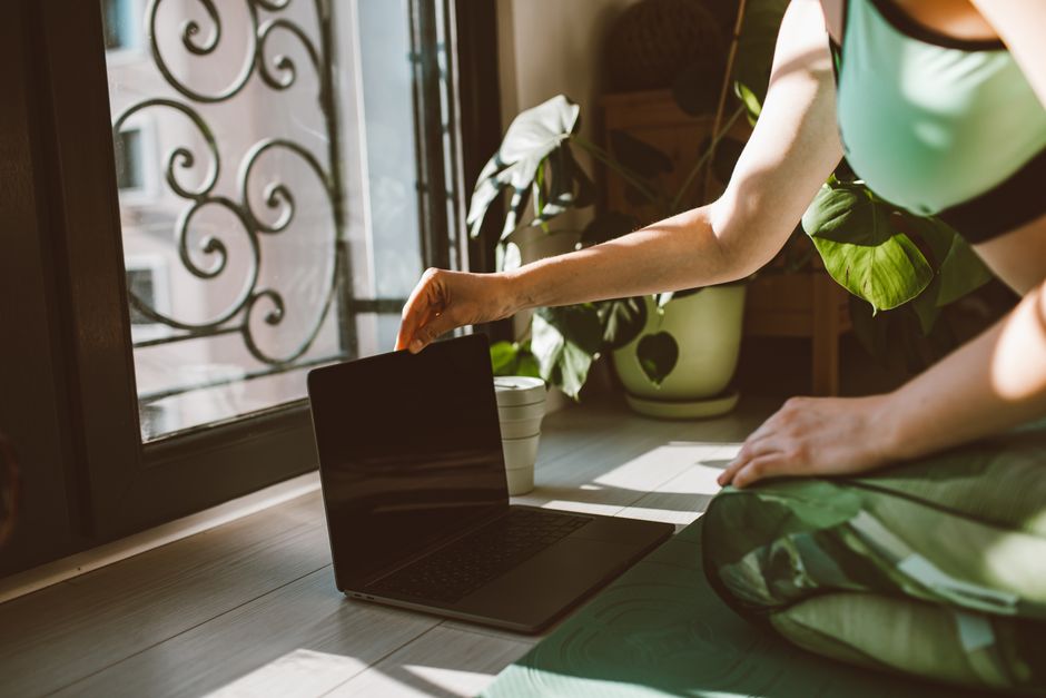 A calm person sitting on the floor in a home office with plants, meditating with eyes closed, promoting mindfulness.