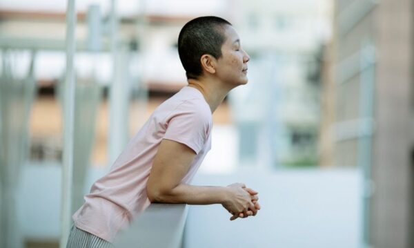 A person practicing mindfulness or meditation on a quiet city balcony at sunrise, overlooking urban buildings, symbolizing a calm start to a weekend reset.