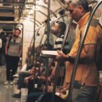 A person on a crowded public transit train reading a book, wearing headphones, demonstrating a calm commute.