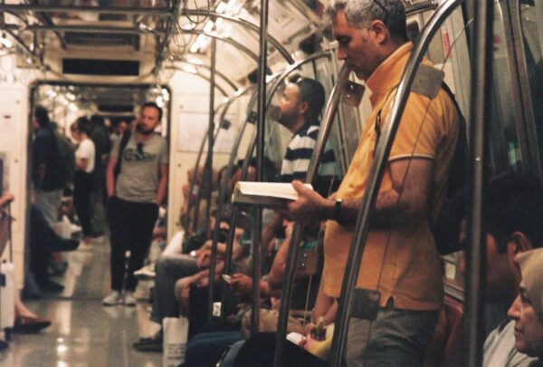 A person on a crowded public transit train reading a book, wearing headphones, demonstrating a calm commute.