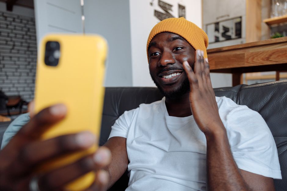 A professional-looking person smiling and looking at the camera during a video call, illuminated by soft, front-facing light.